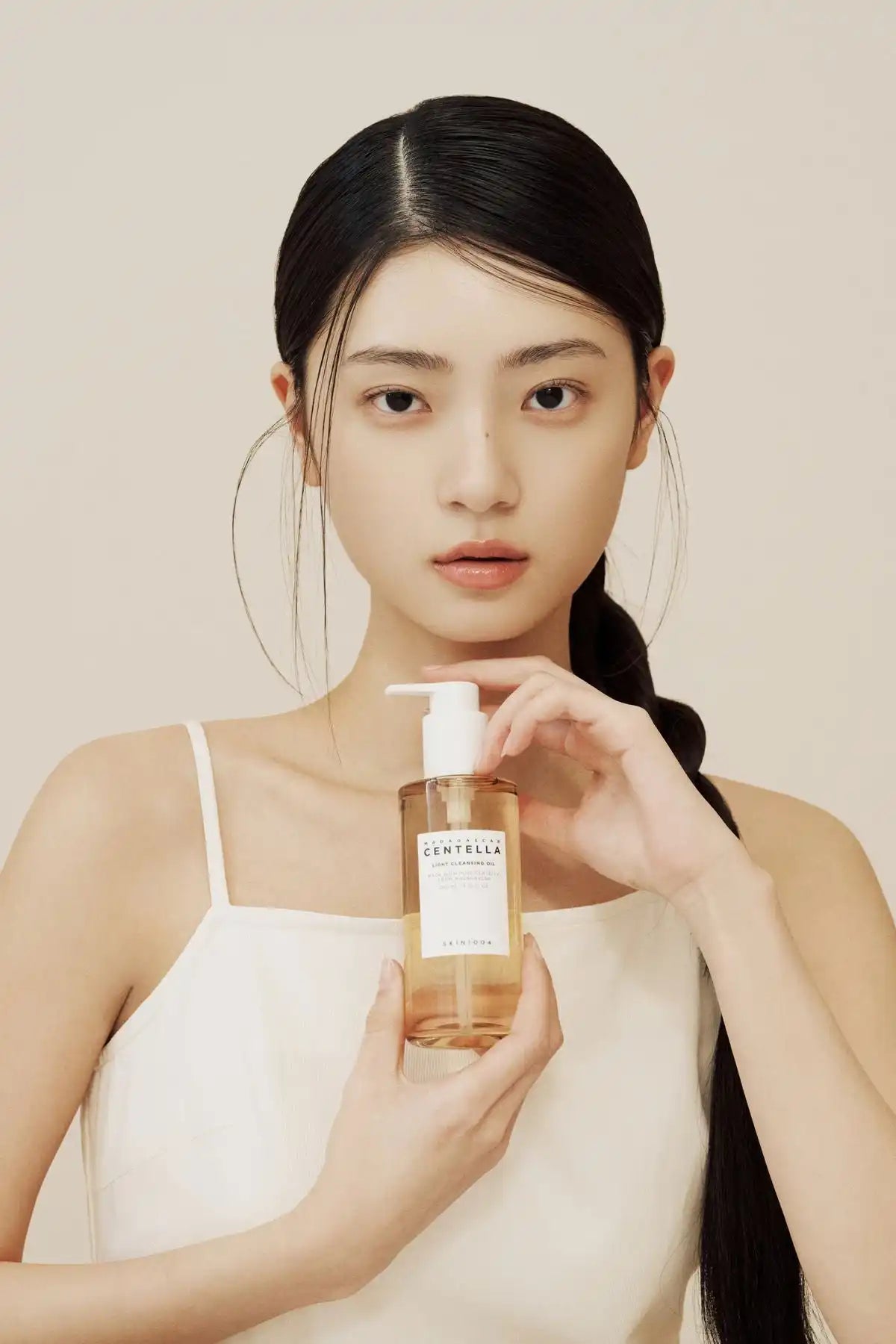 A skincare product in a clear bottle with a white pump dispenser.