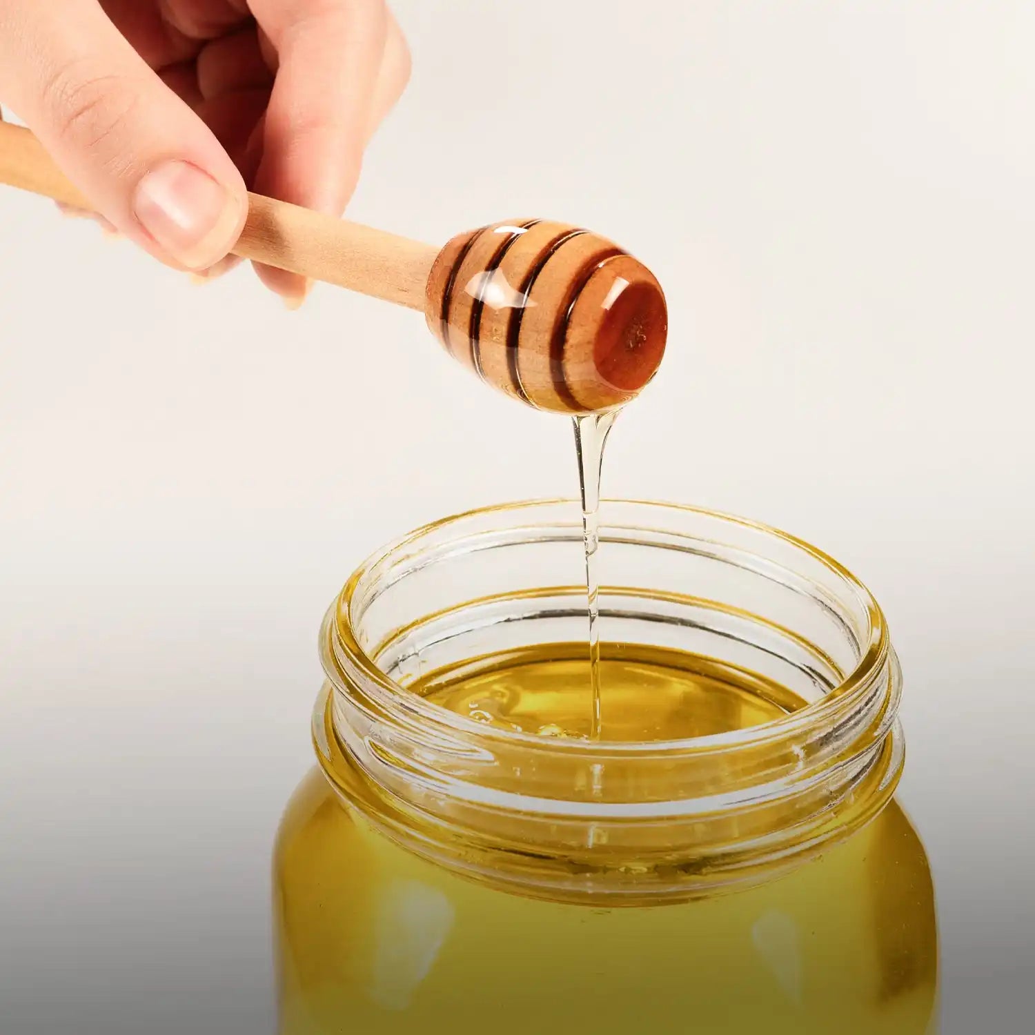 Wooden honey dipper with striped design and natural finish.