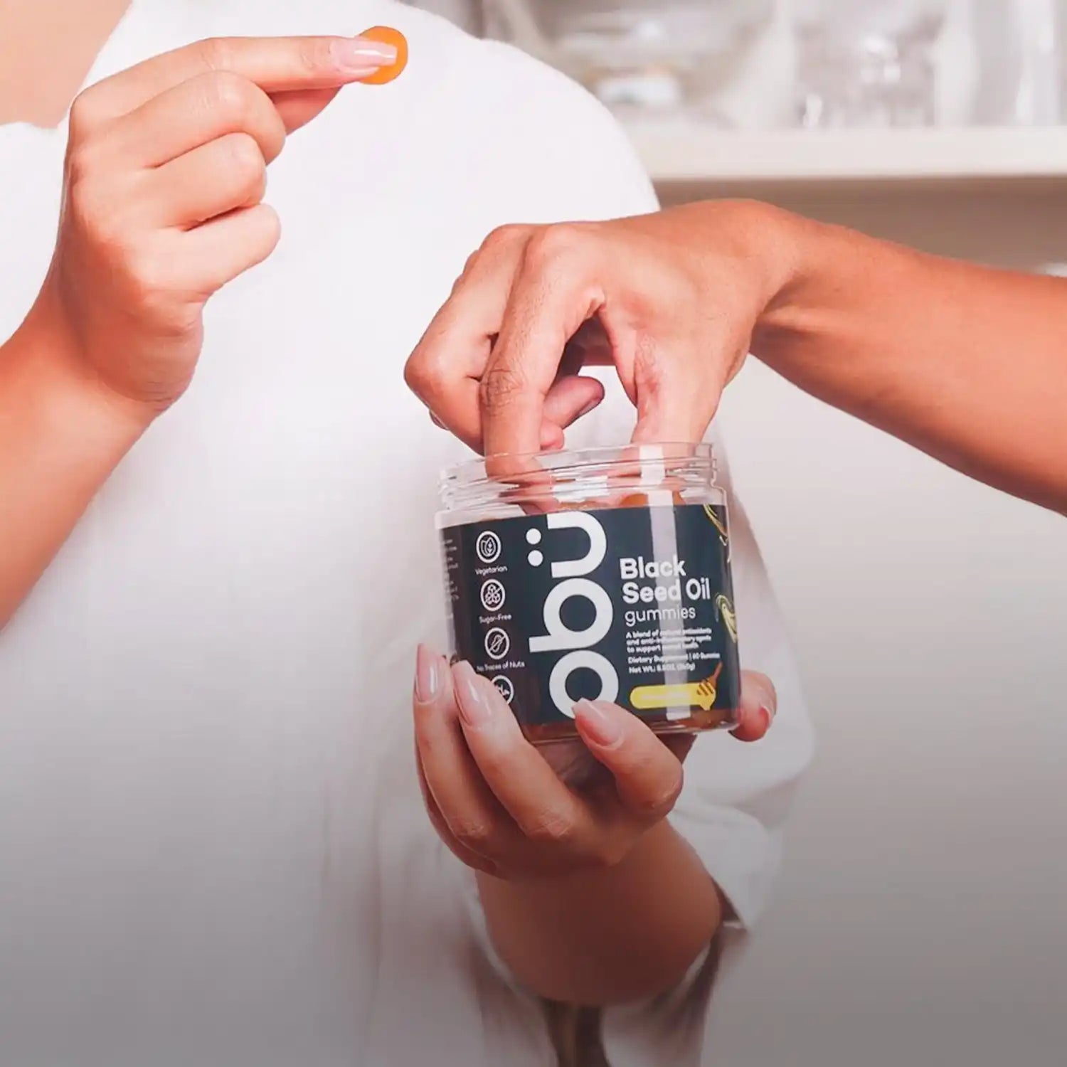 Black seed oil gummies jar with orange cap and green label.