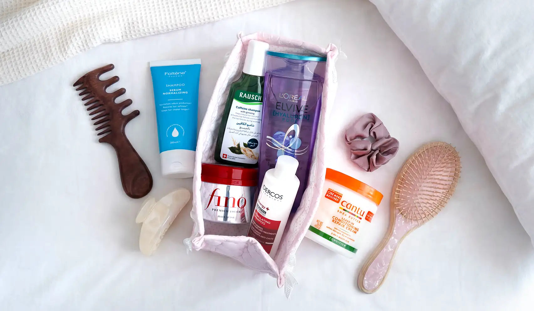 Pink fabric pouch containing various hair care products and tools