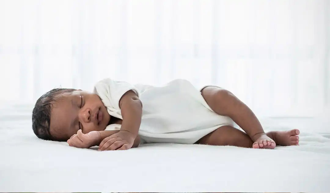 Sleeping baby in white onesie.