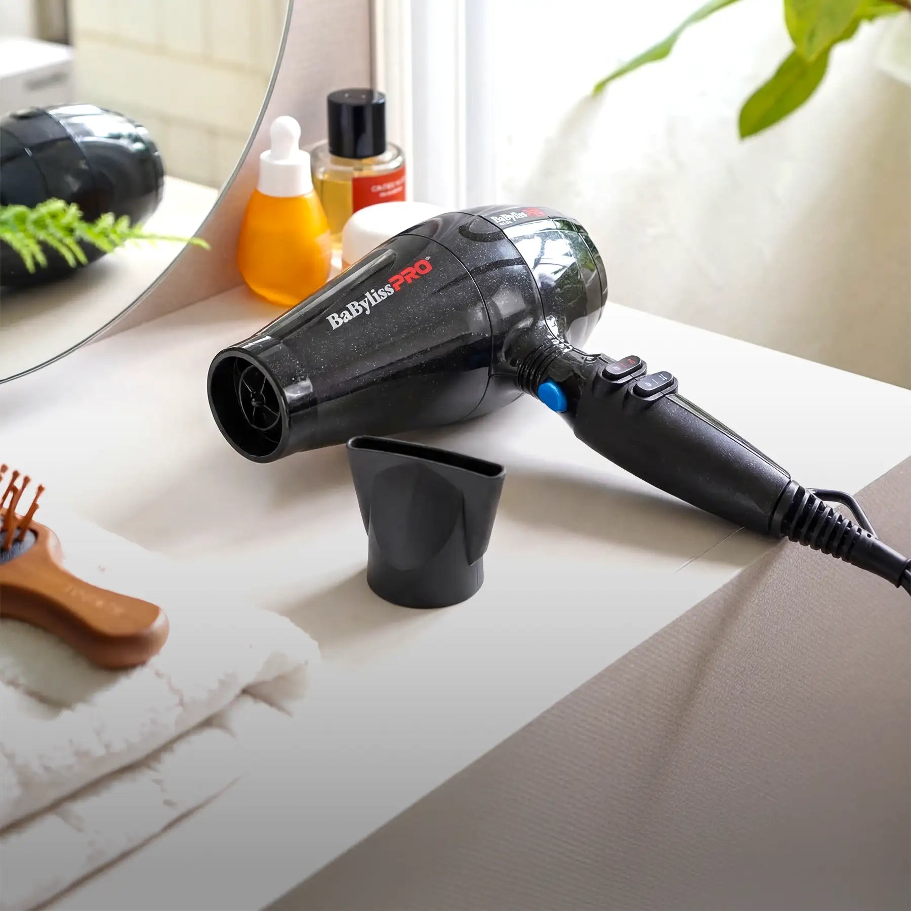 Black babyliss pro hair dryer with a glossy finish and blue accent button.