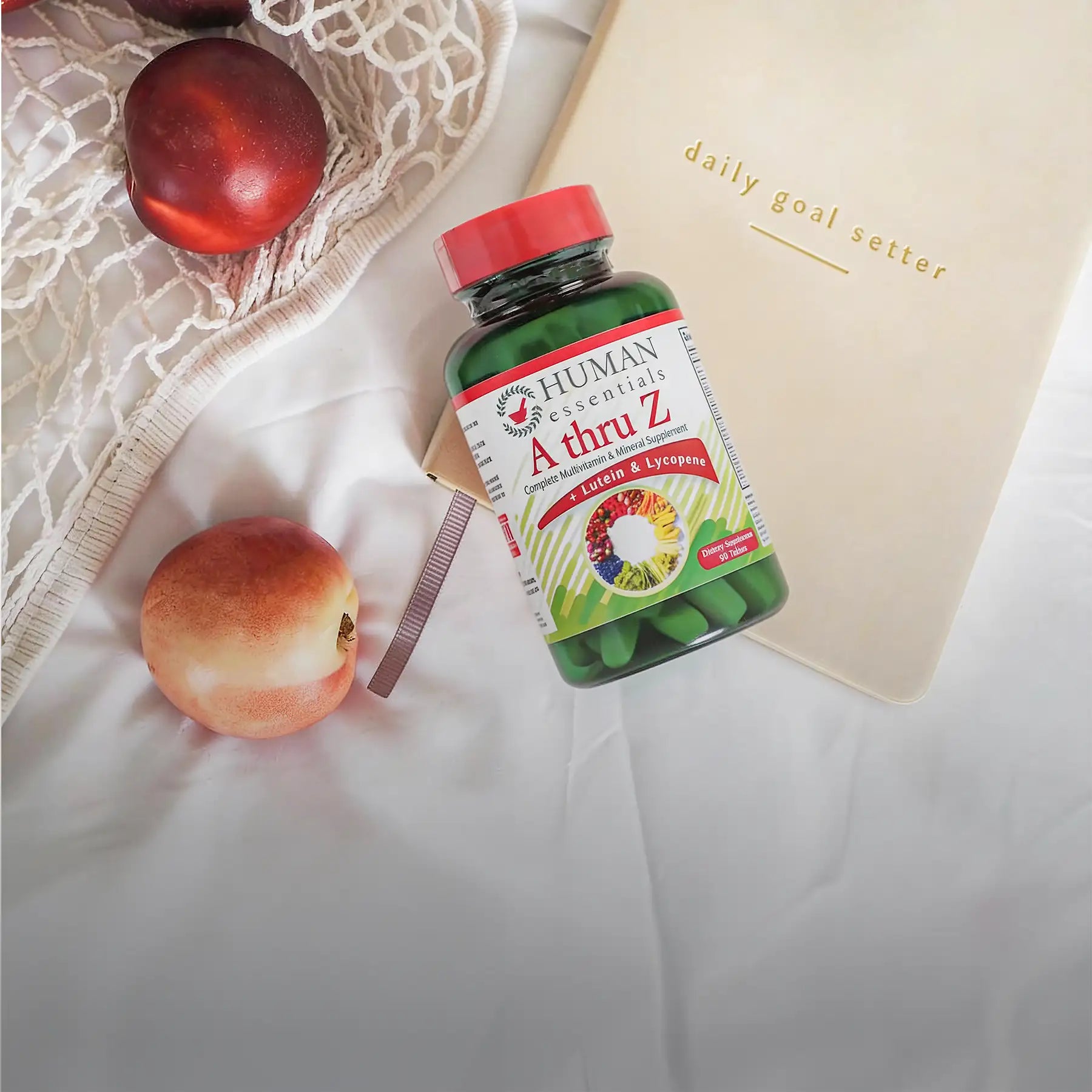 Green bottle of human essentials a thru z multivitamin and mineral supplement with a red cap.