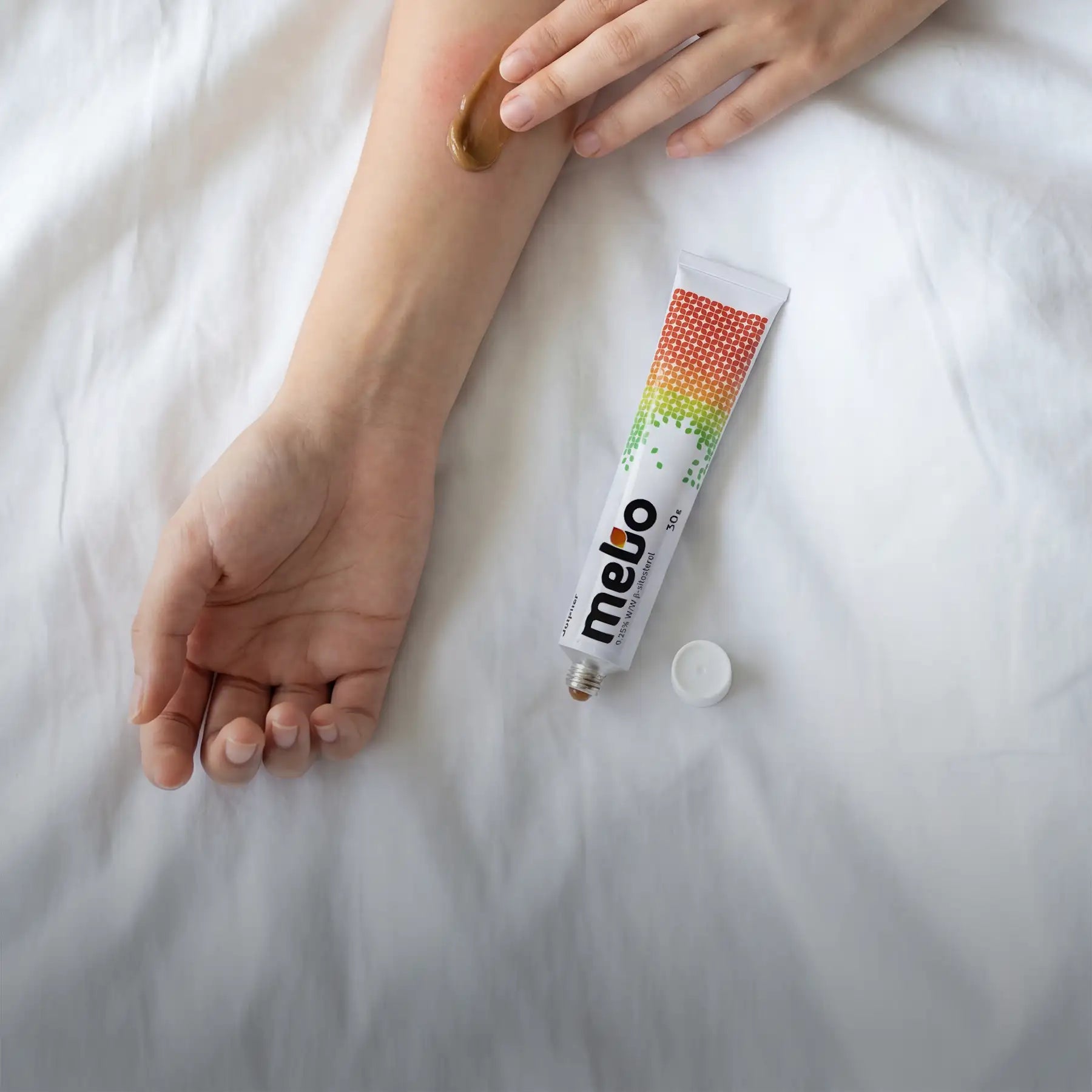 A white tube of meto brand cream with a colorful gradient pattern and green dot design, featuring the text ’30g’ on its side.