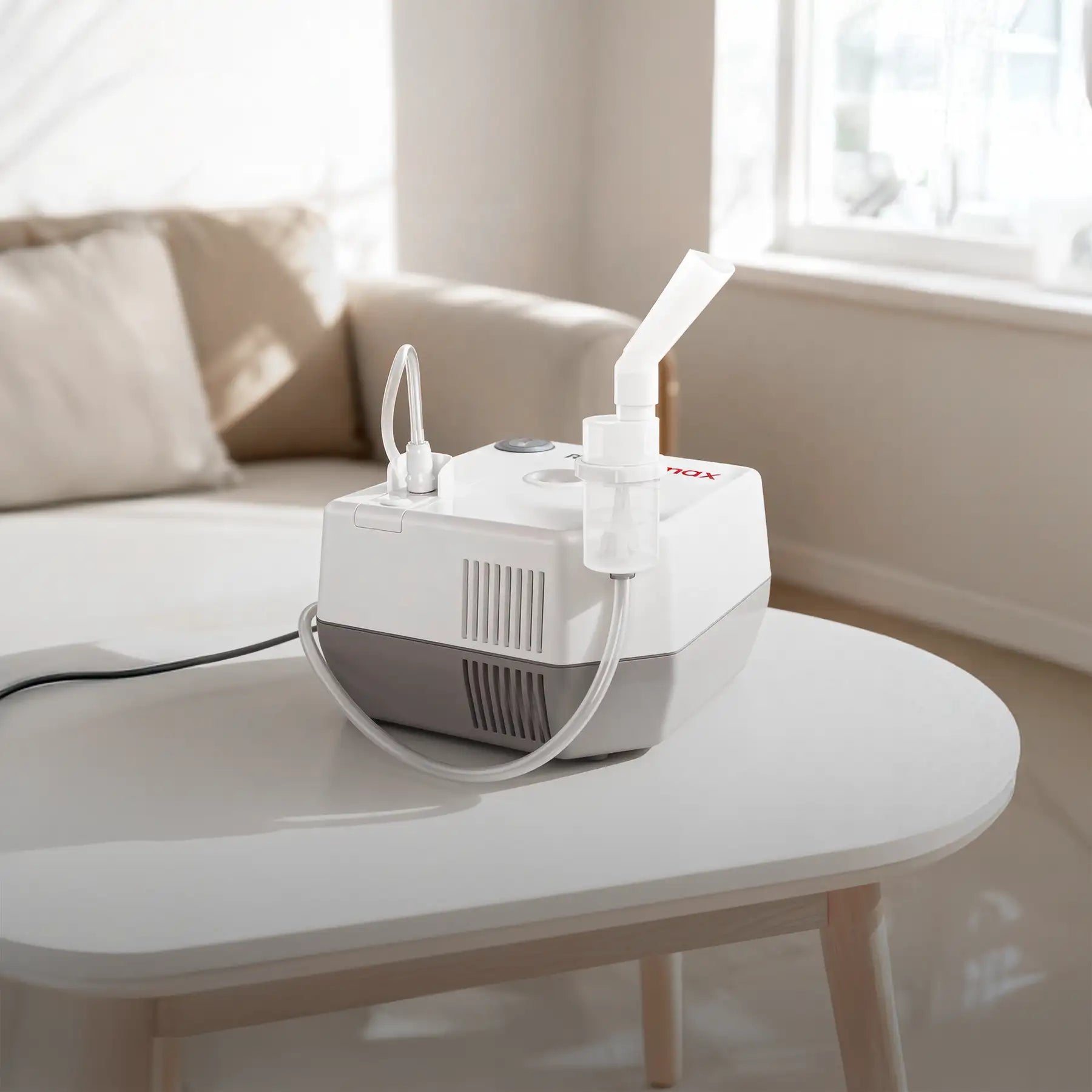 White and gray nebulizer machine with a clear medication chamber and attached tubing.