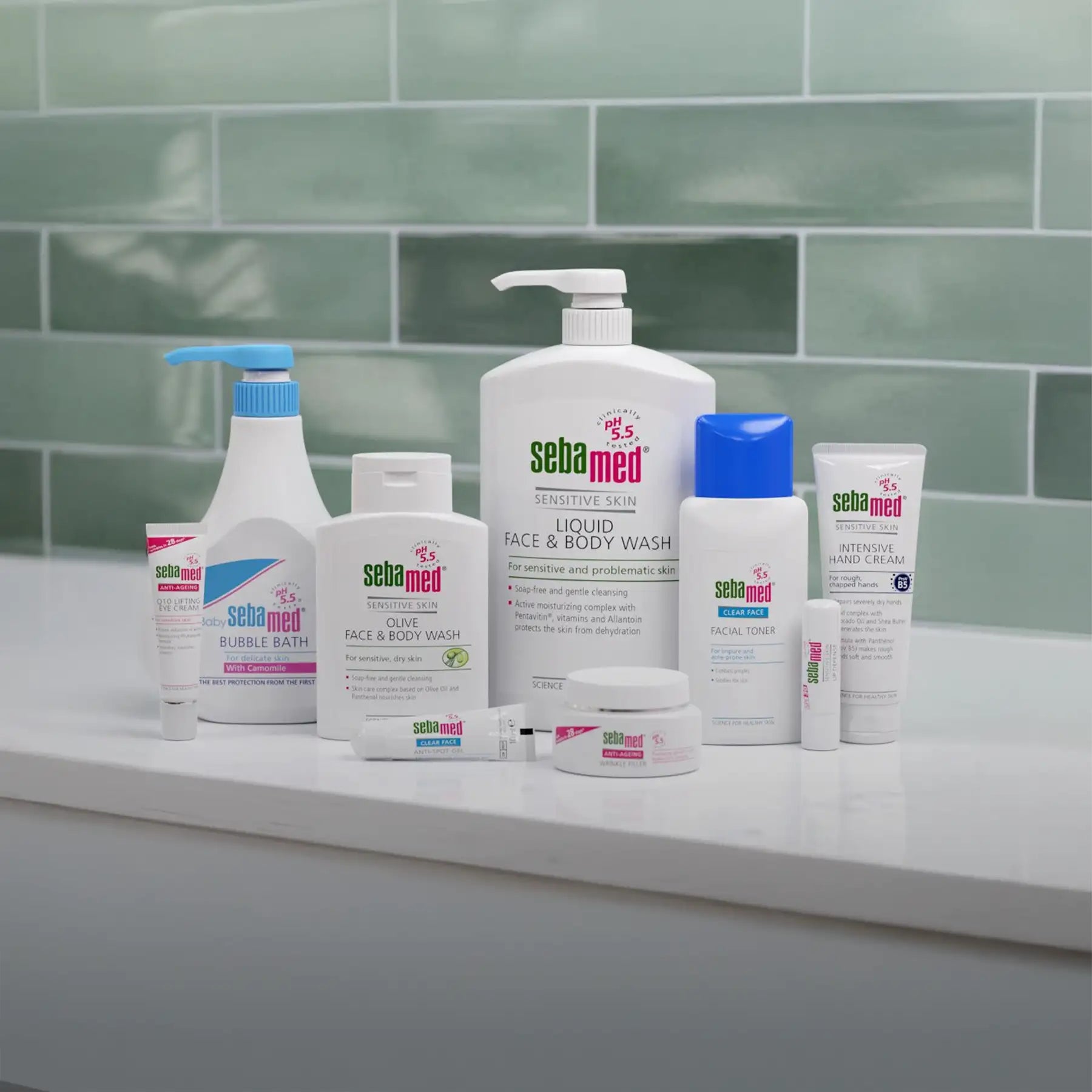 White sebamed skincare products with blue and pink accents, including a pump bottle, tubes, jars, and bottles of various sizes.
