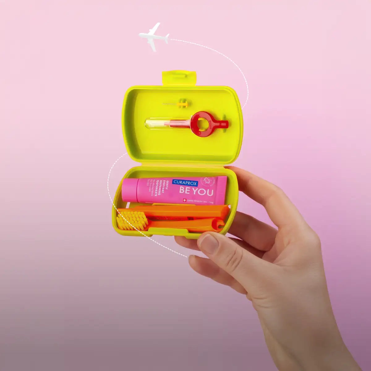 Bright lime green compact travel case holding a pink curaprox beyou toothpaste, orange toothbrush, and red keychain.