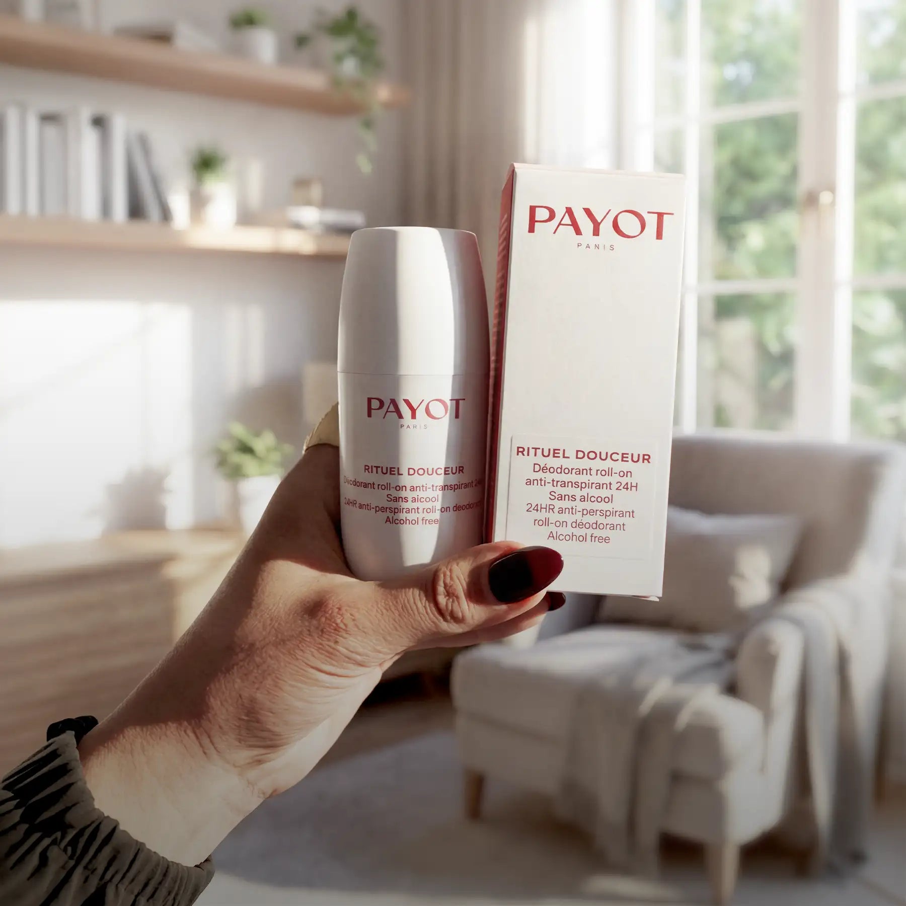 A sleek white payot paris rituels douceur deodorant roll-on with a minimalist design and red branding, held beside its matching box.