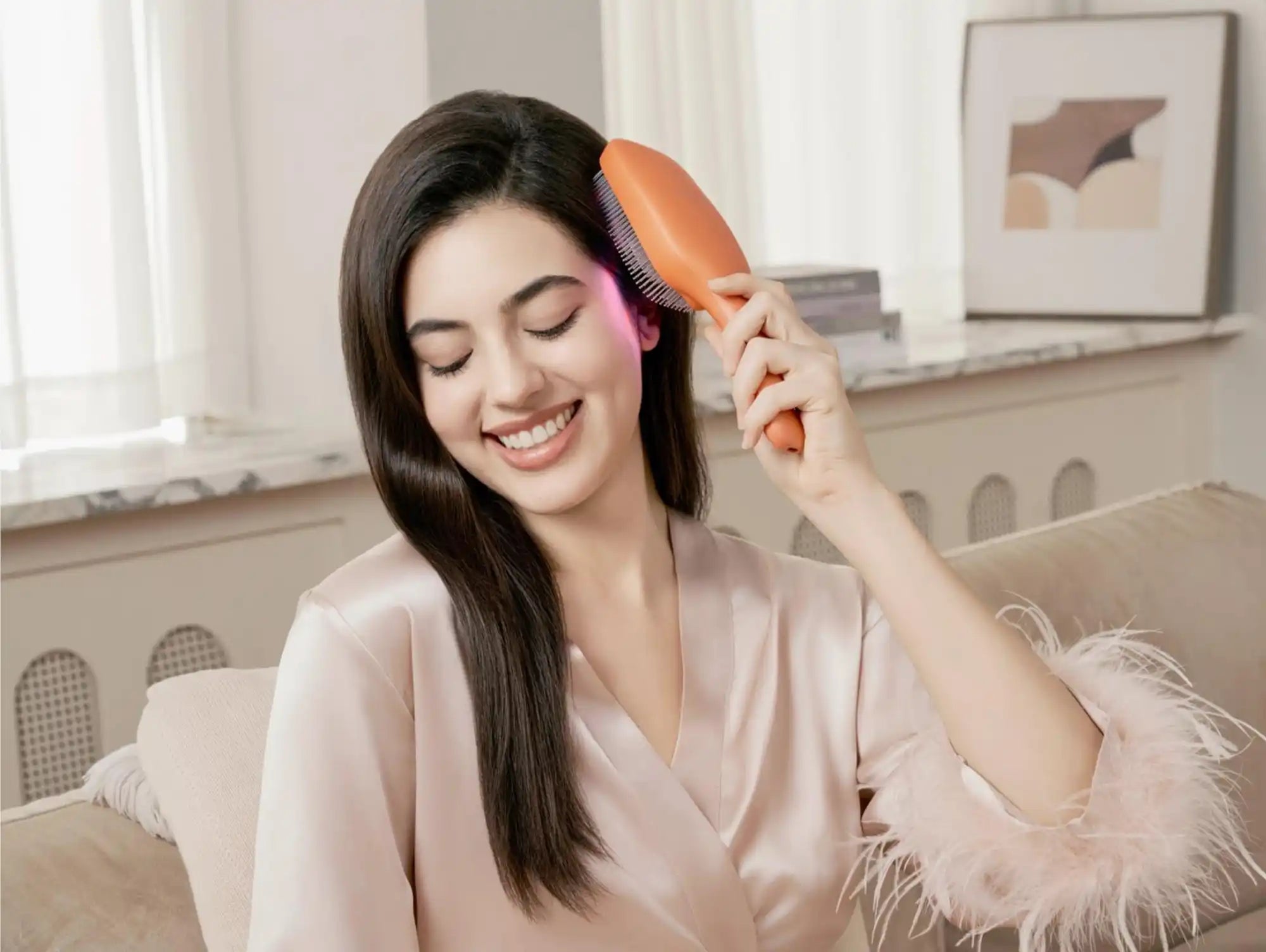 A woman with long, dark hair brushing it with an orange hairbrush that emits a pink light.