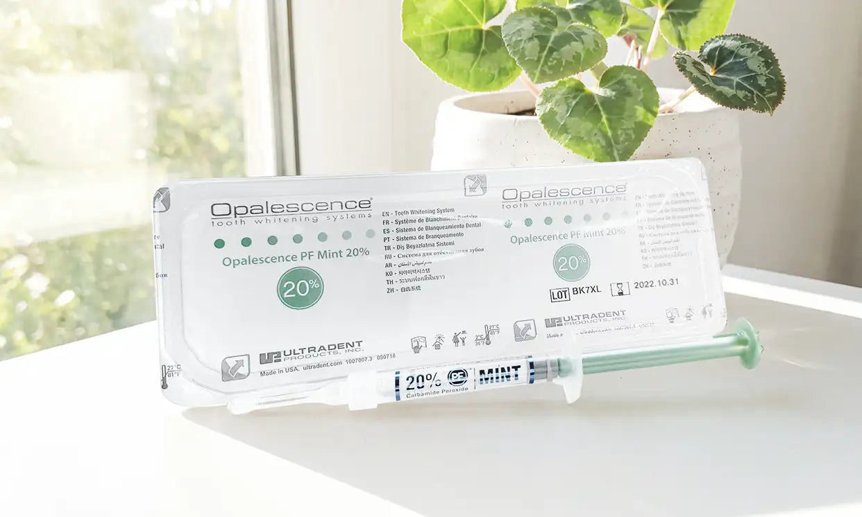 A white and green opalescence tooth whitening gel syringe with a 20% concentration, mint flavor, packaged in a clear plastic sleeve.