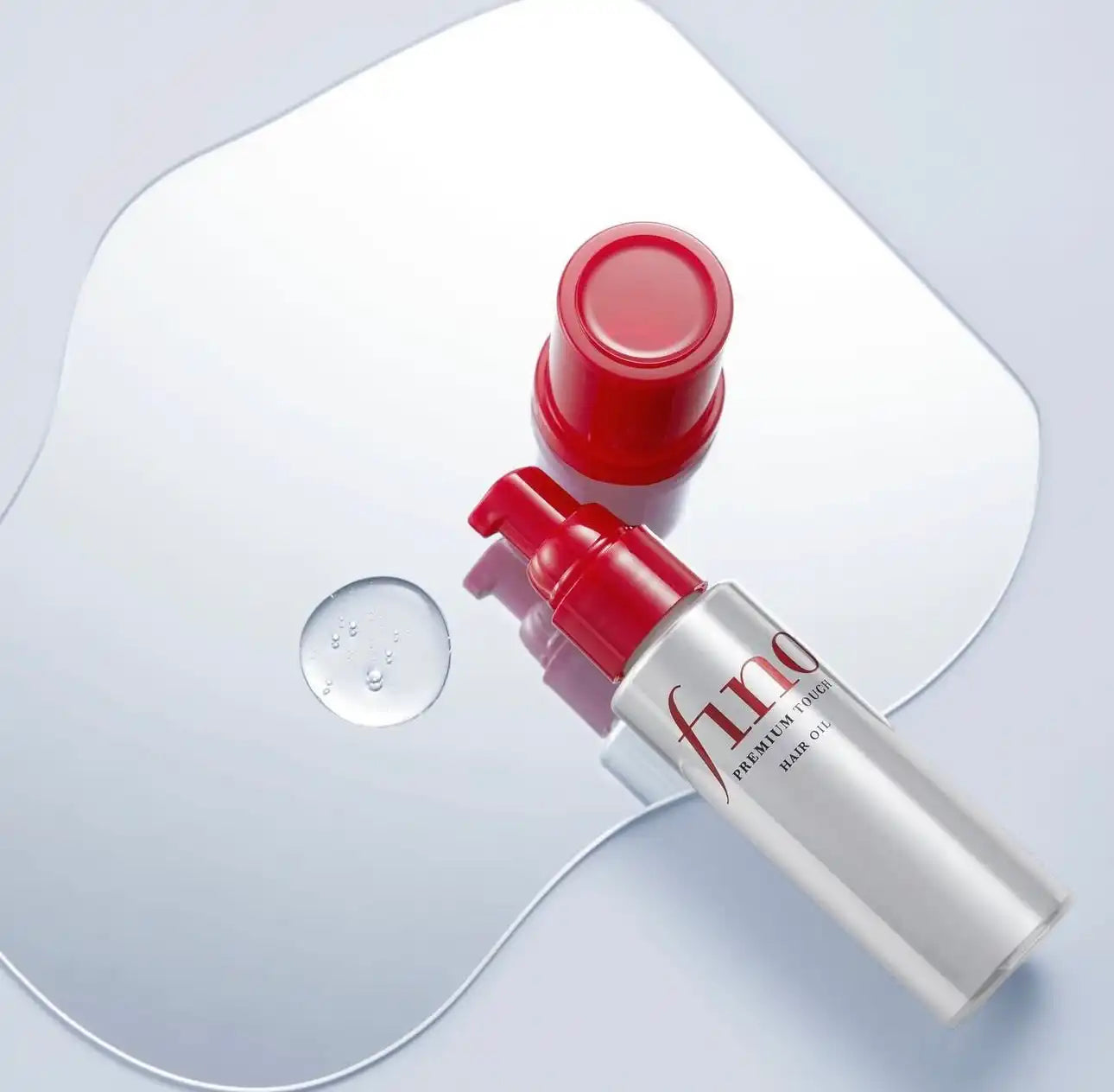 Hair oil bottle with red pump.