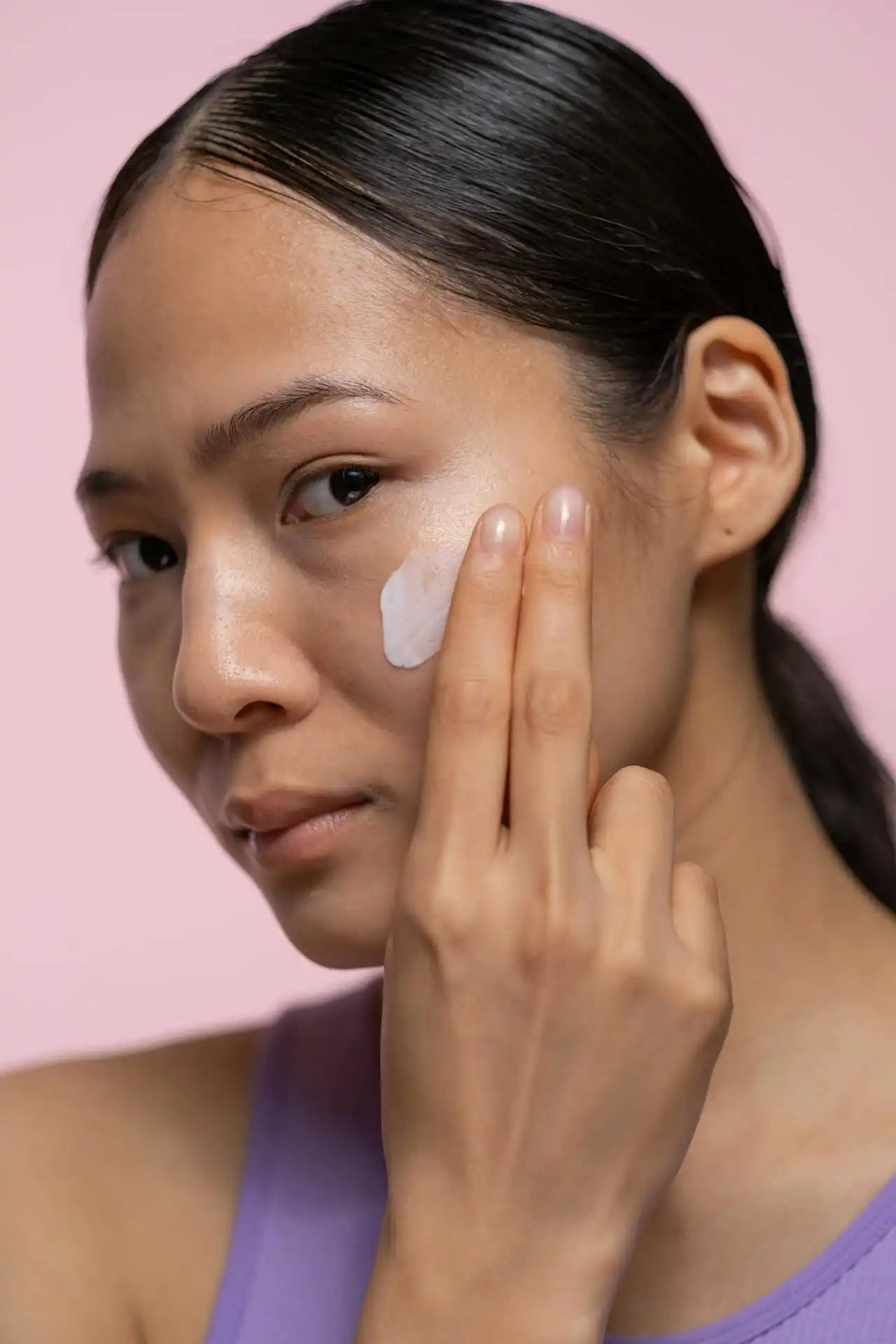 Woman applying facial cream.