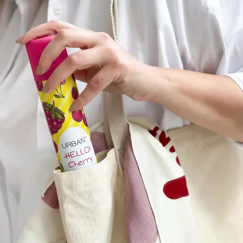 A vibrant yellow spray can with a pink cap, adorned with red raspberry and cherry illustrations.